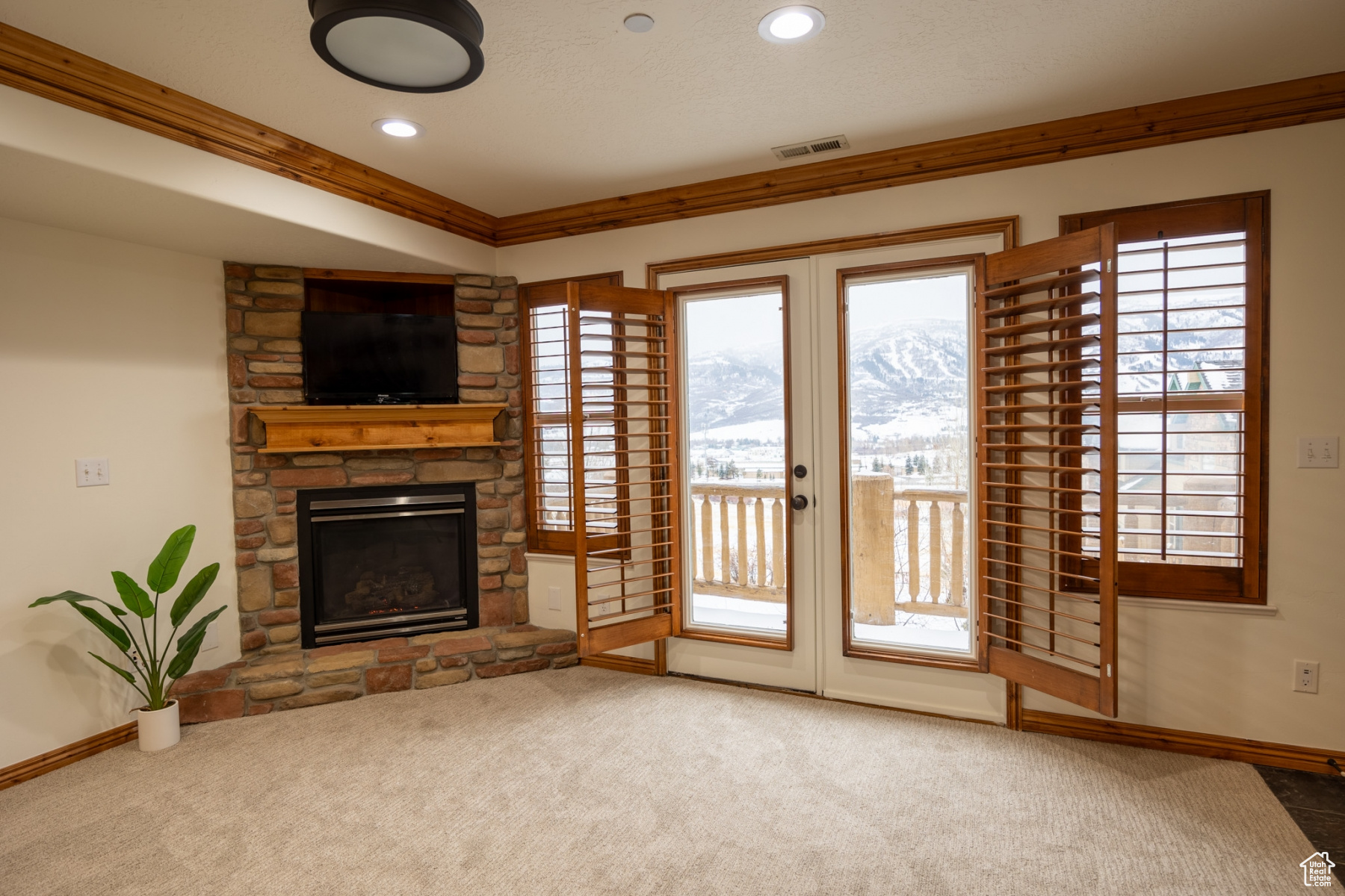 Unfurnished living room featuring carpet, a fireplace, and crown molding