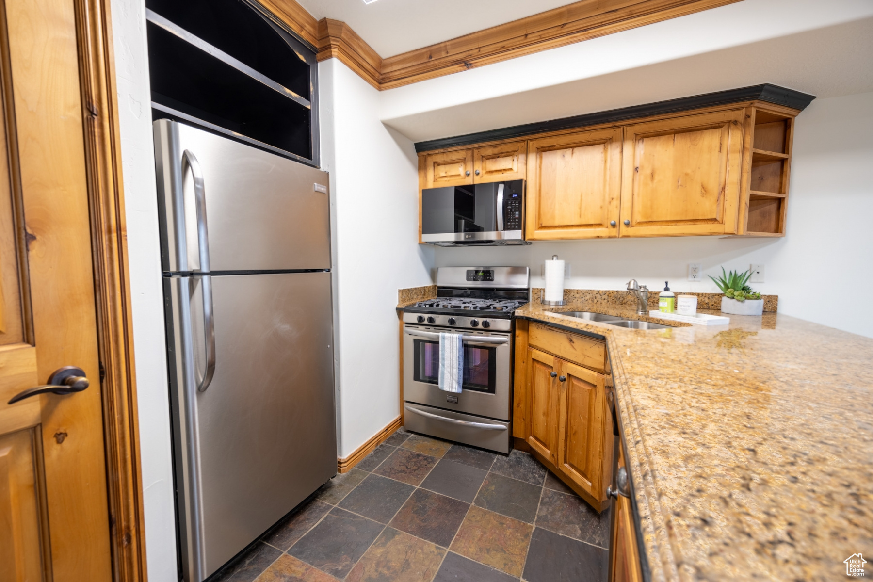 Kitchen featuring sink, ornamental molding, and appliances with stainless steel finishes