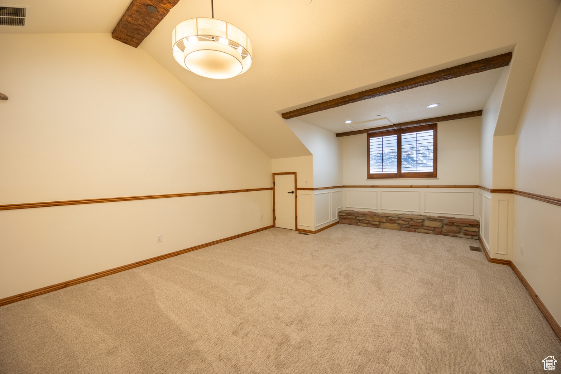 Additional living space featuring lofted ceiling with beams and light colored carpet