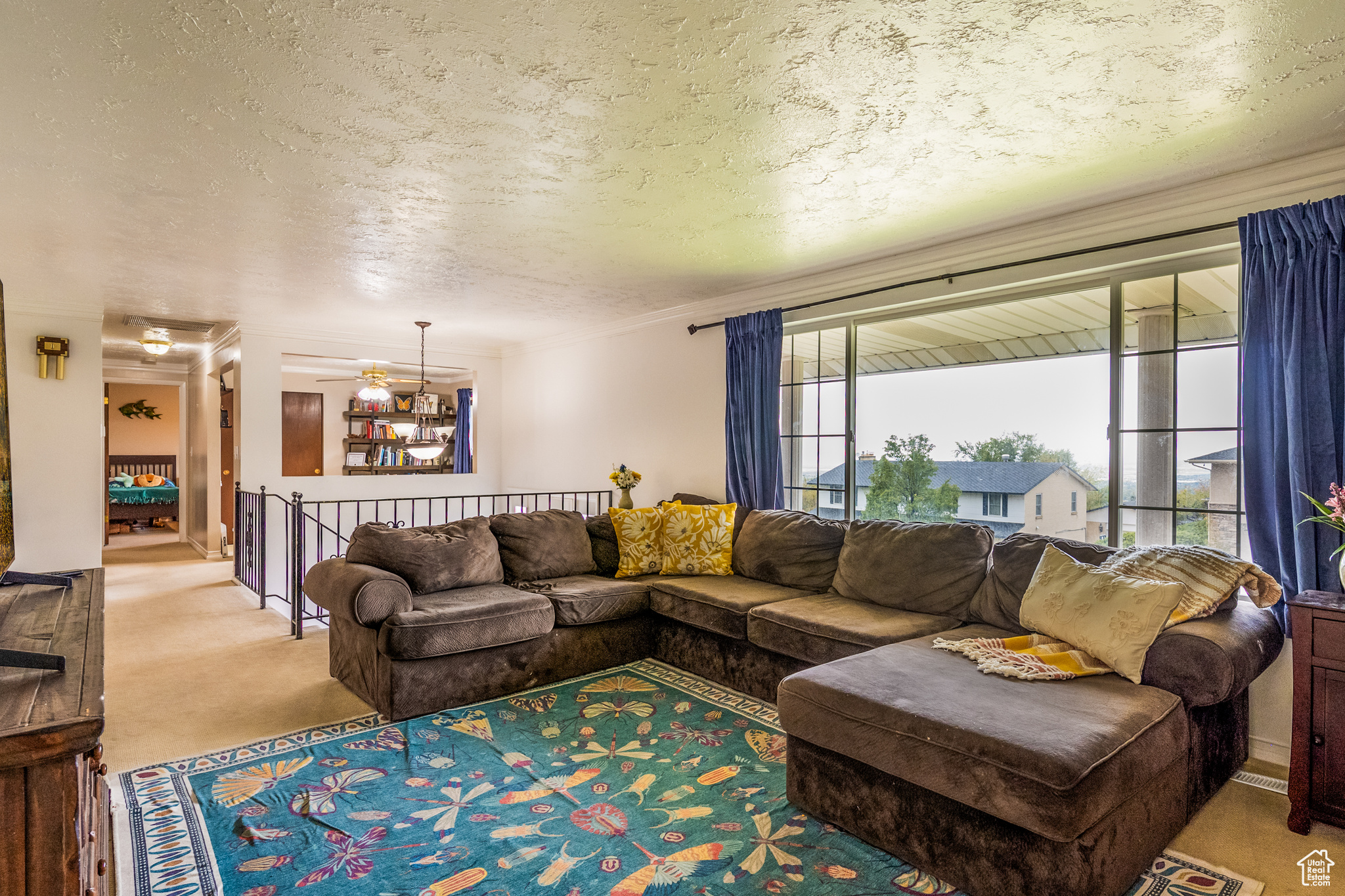 Carpeted living room featuring ceiling fan and a textured ceiling