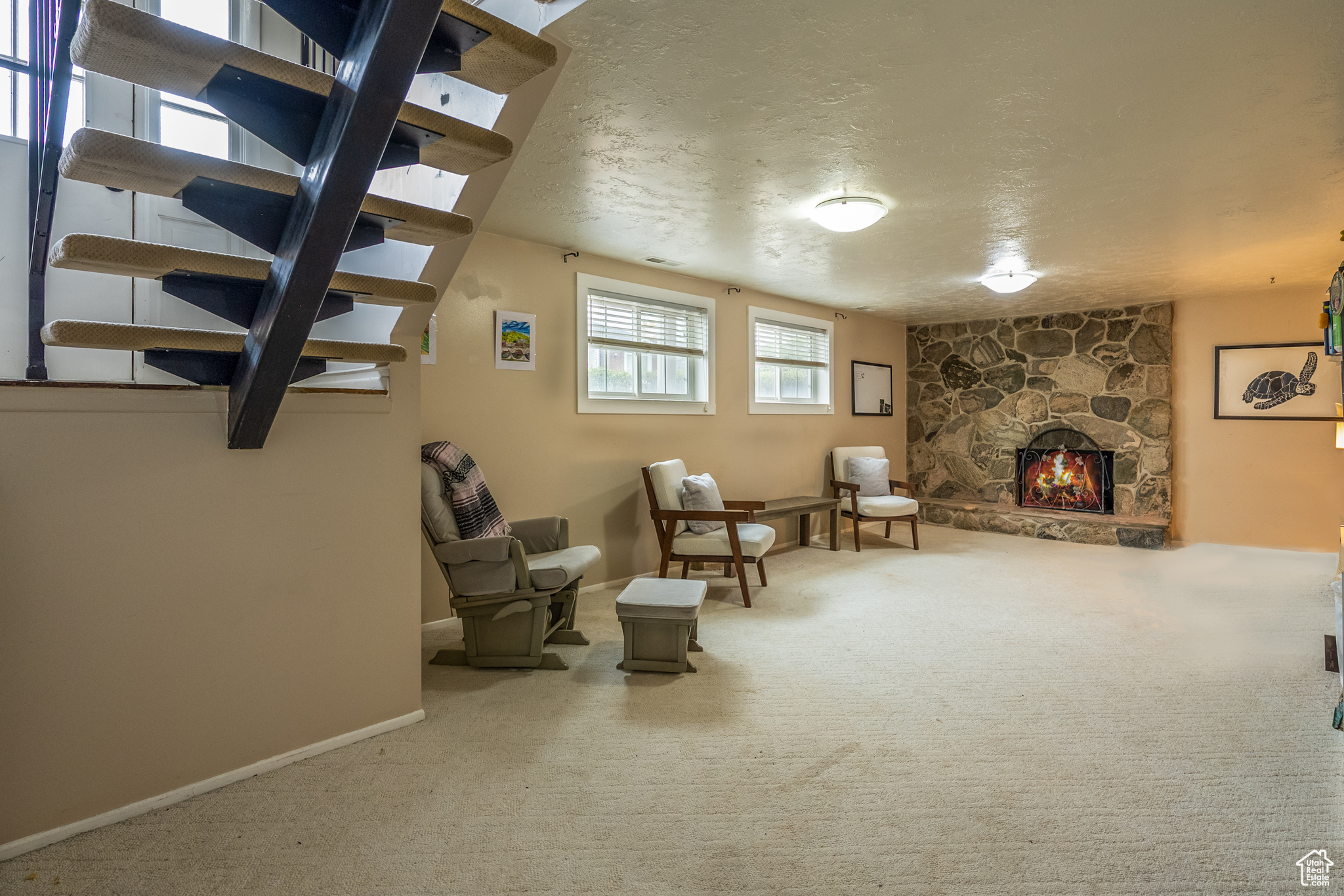 Sitting room featuring carpet flooring, a textured ceiling, and a stone fireplace