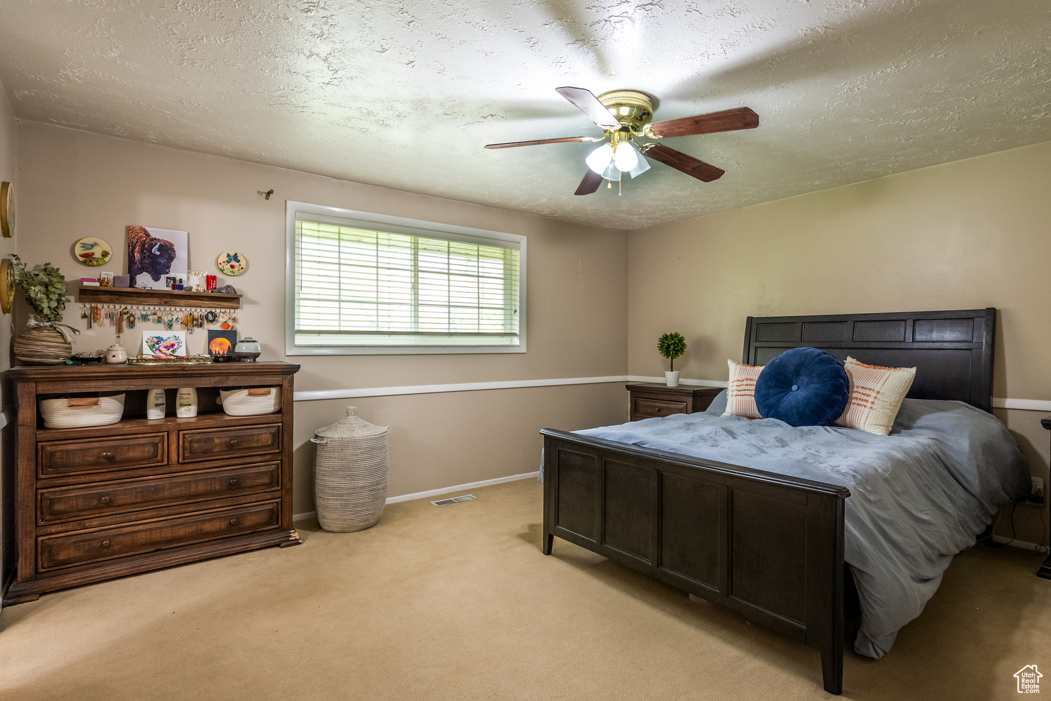 Carpeted bedroom with ceiling fan and a textured ceiling