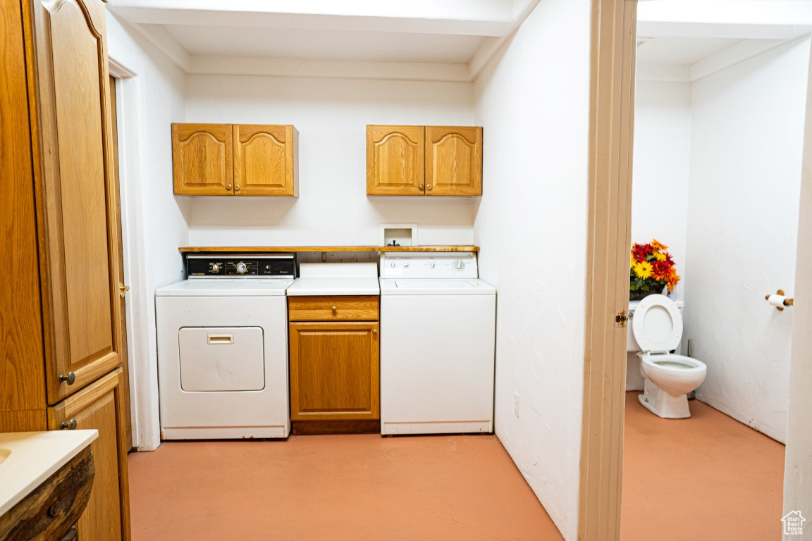 Washroom featuring cabinets and washing machine and dryer