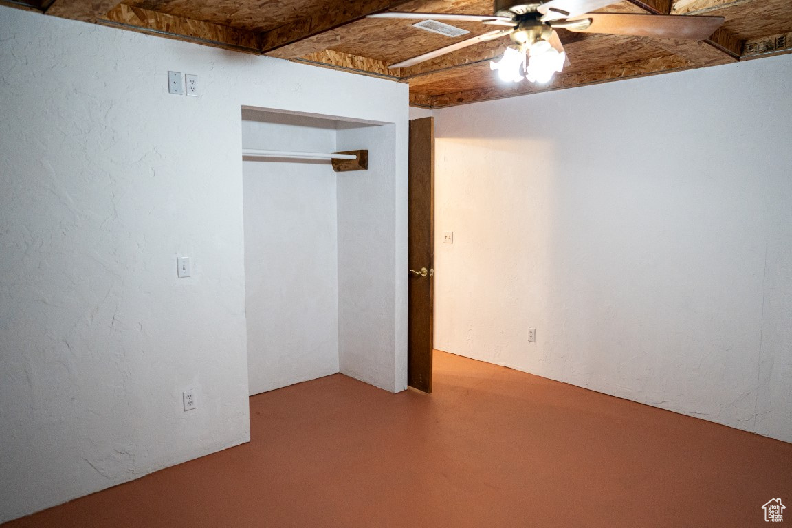 Unfurnished bedroom featuring ceiling fan, a closet, and concrete floors