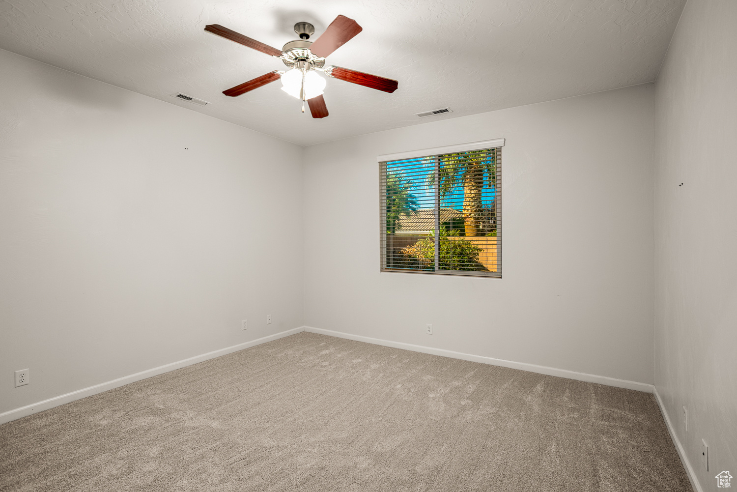 Empty room featuring carpet flooring and ceiling fan