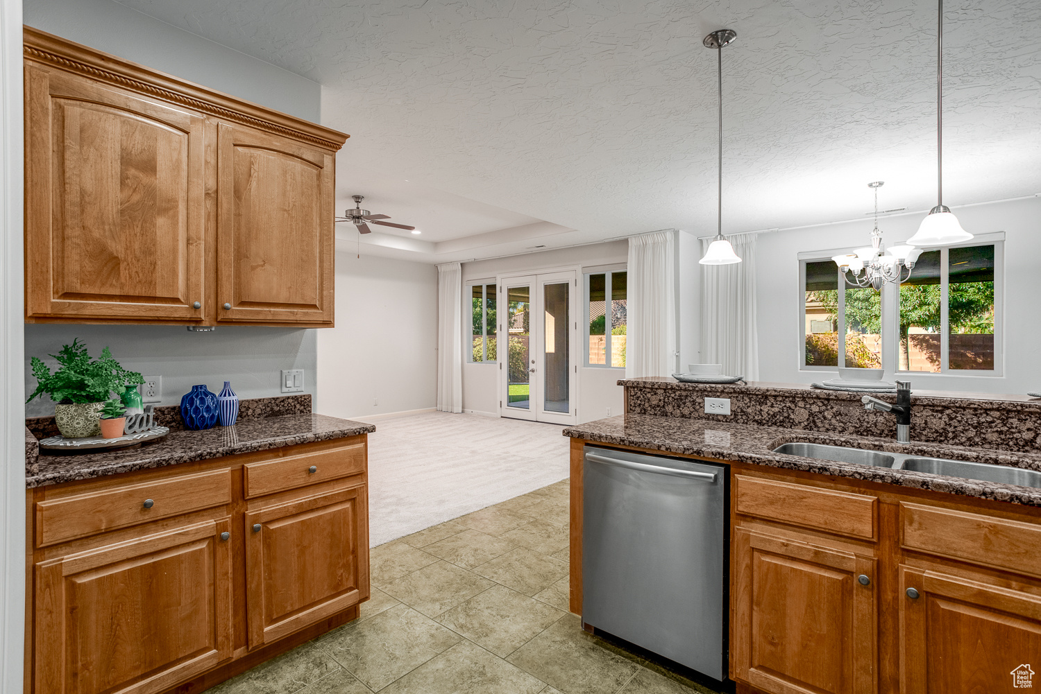 Kitchen with sink, stainless steel dishwasher, decorative light fixtures, a tray ceiling, and ceiling fan with notable chandelier