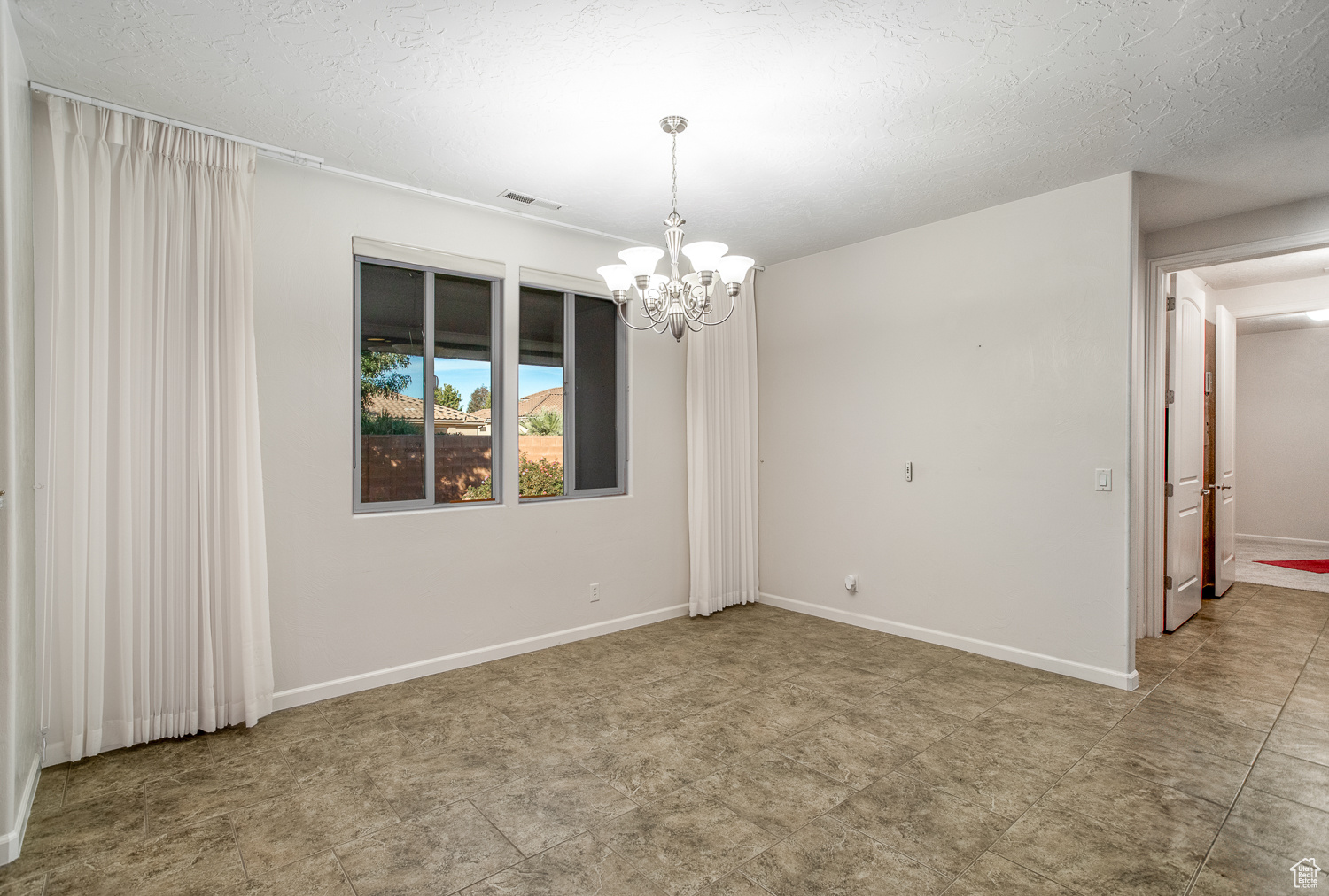 Spare room with a textured ceiling and an inviting chandelier