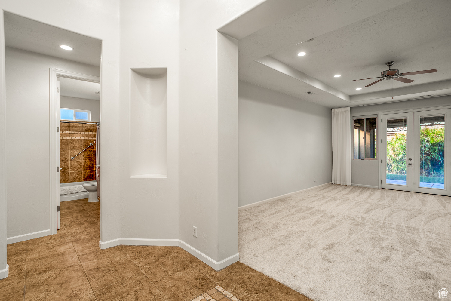 Interior space with french doors, a raised ceiling, and ceiling fan