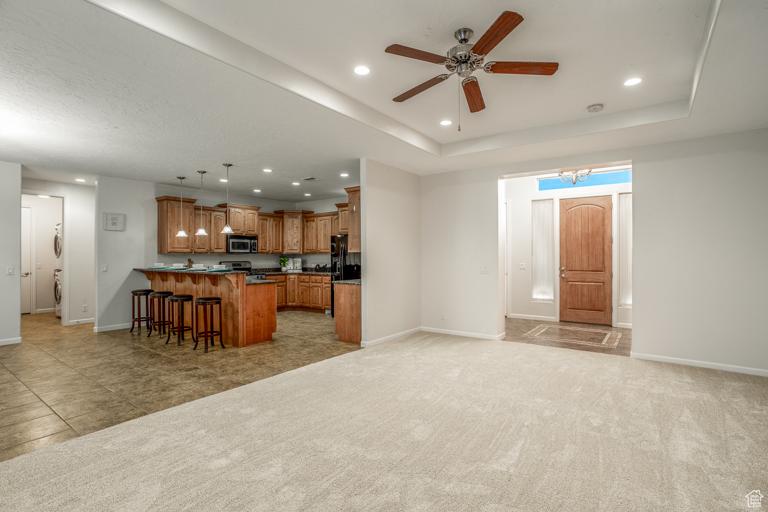 Carpeted living room featuring a tray ceiling and ceiling fan