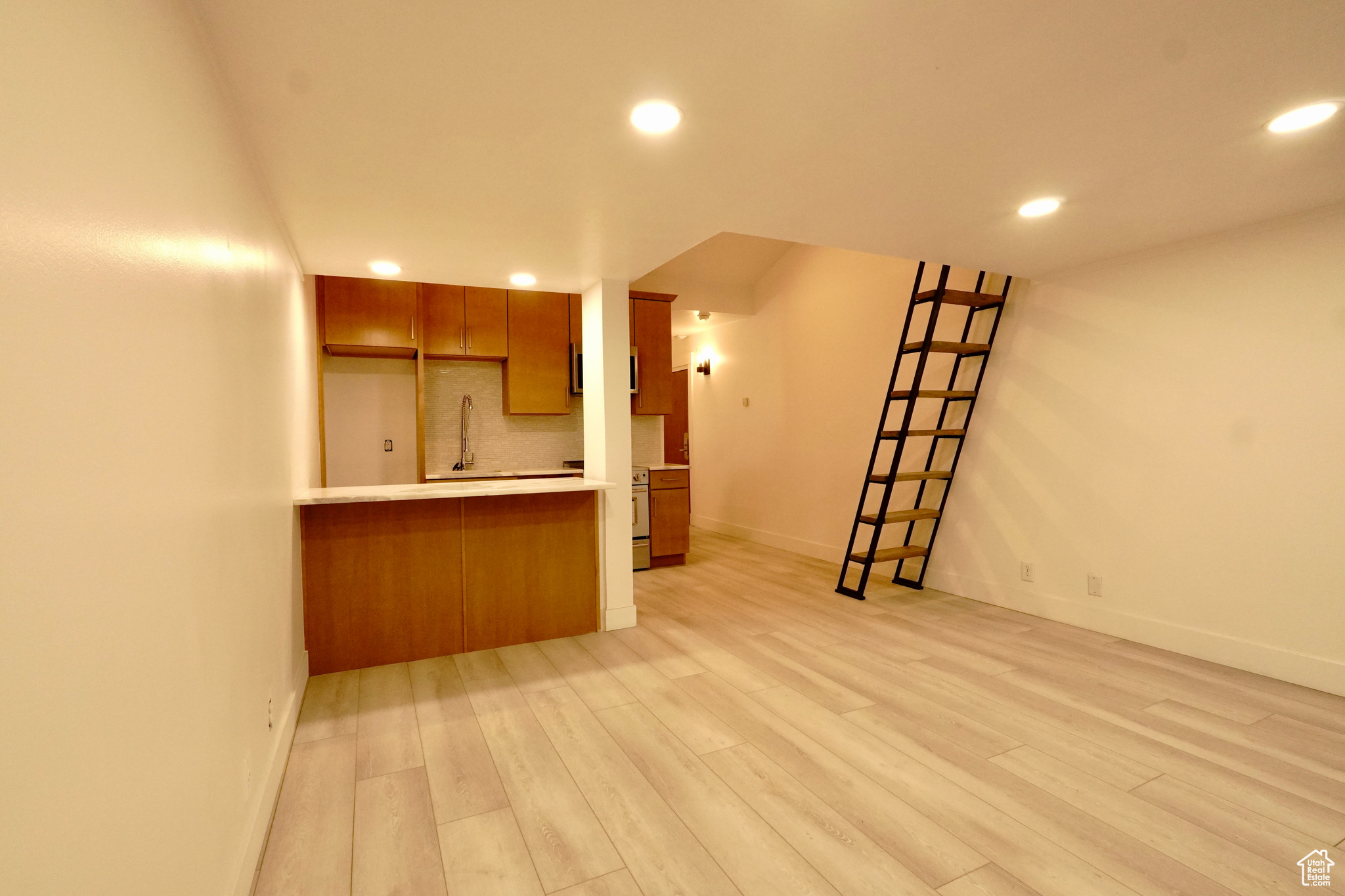 Kitchen featuring kitchen peninsula, light wood-type flooring, and backsplash