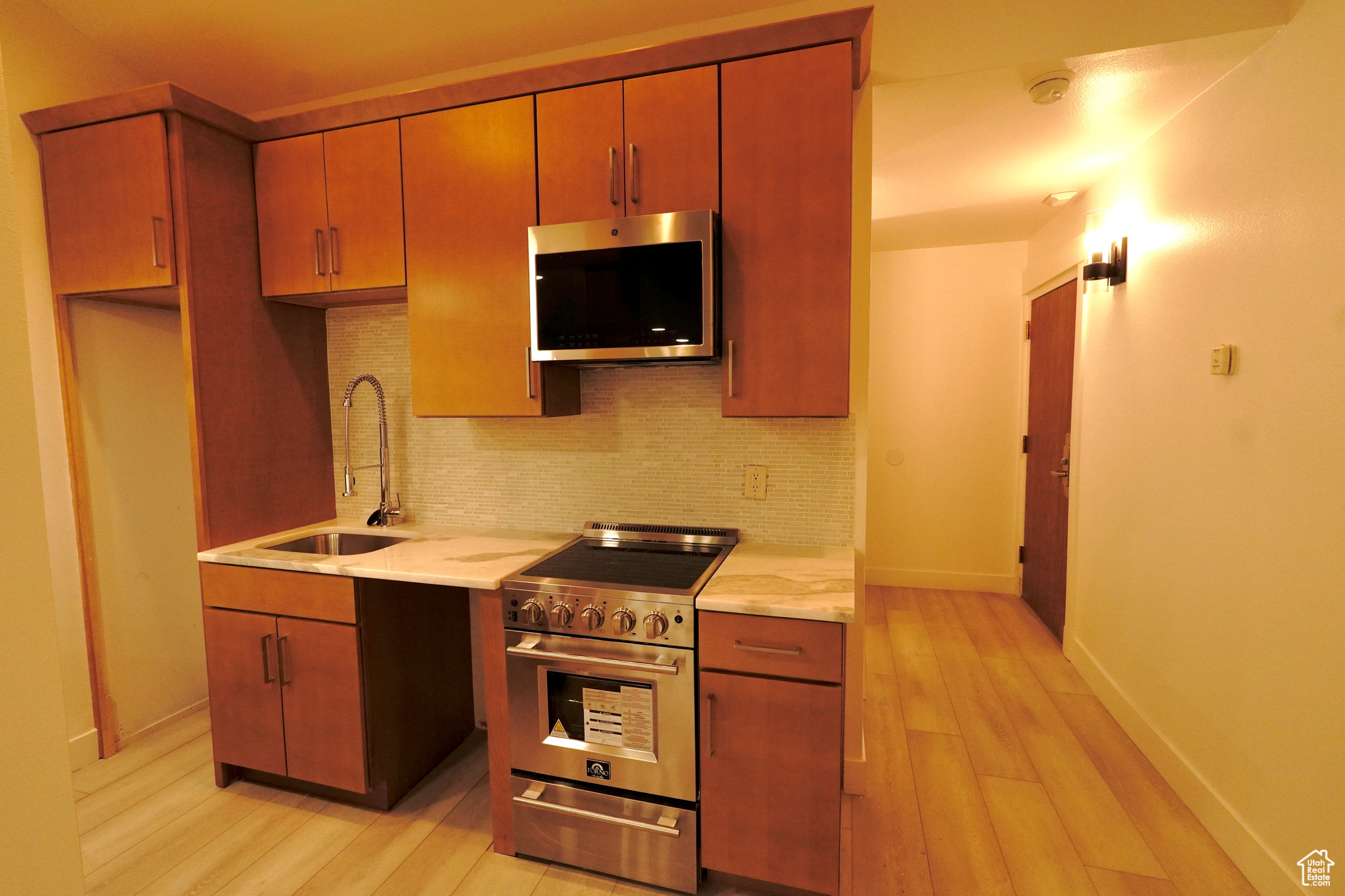 Kitchen with decorative backsplash, sink, appliances with stainless steel finishes, and light hardwood / wood-style flooring