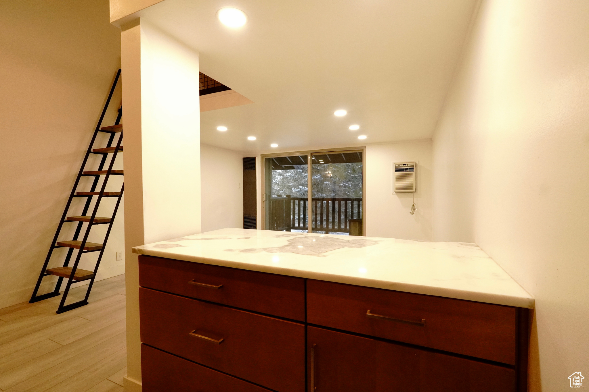 Kitchen featuring light stone countertops, light hardwood / wood-style floors, kitchen peninsula, and a wall mounted AC