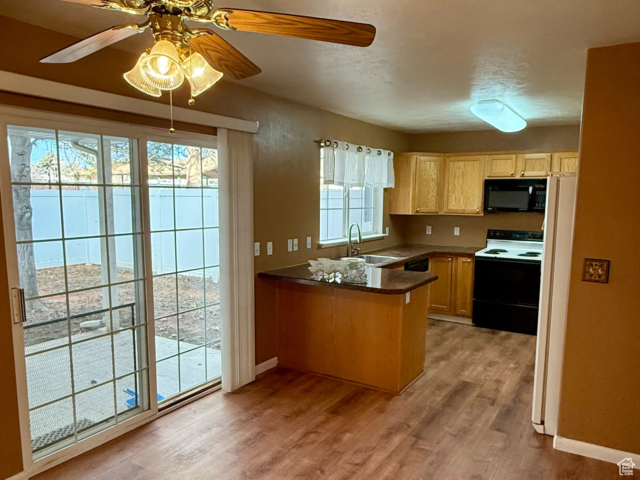 Kitchen featuring ceiling fan, sink, light hardwood / wood-style flooring, kitchen peninsula, and white appliances