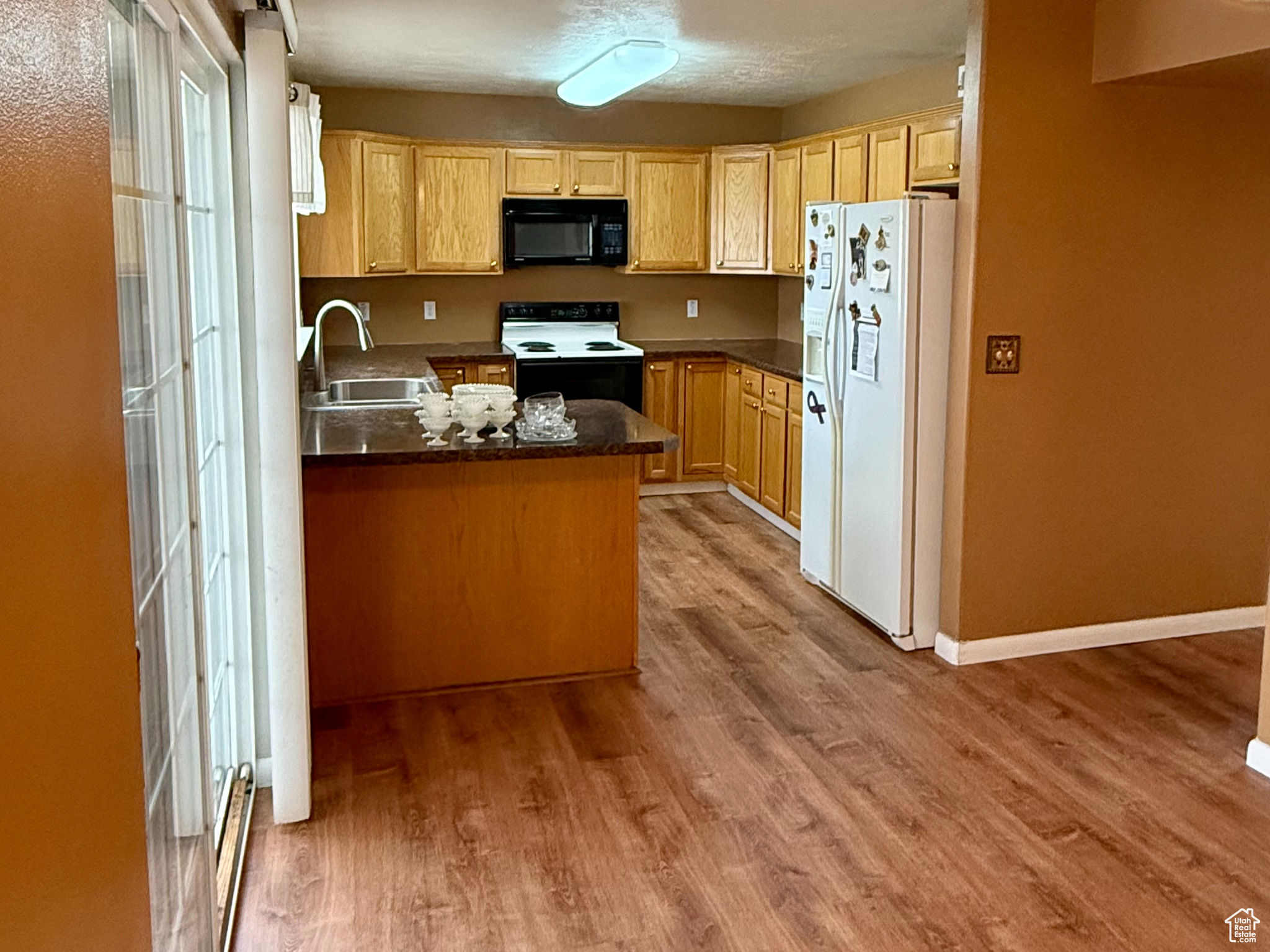 Kitchen with sink, white appliances, kitchen peninsula, and light hardwood / wood-style flooring