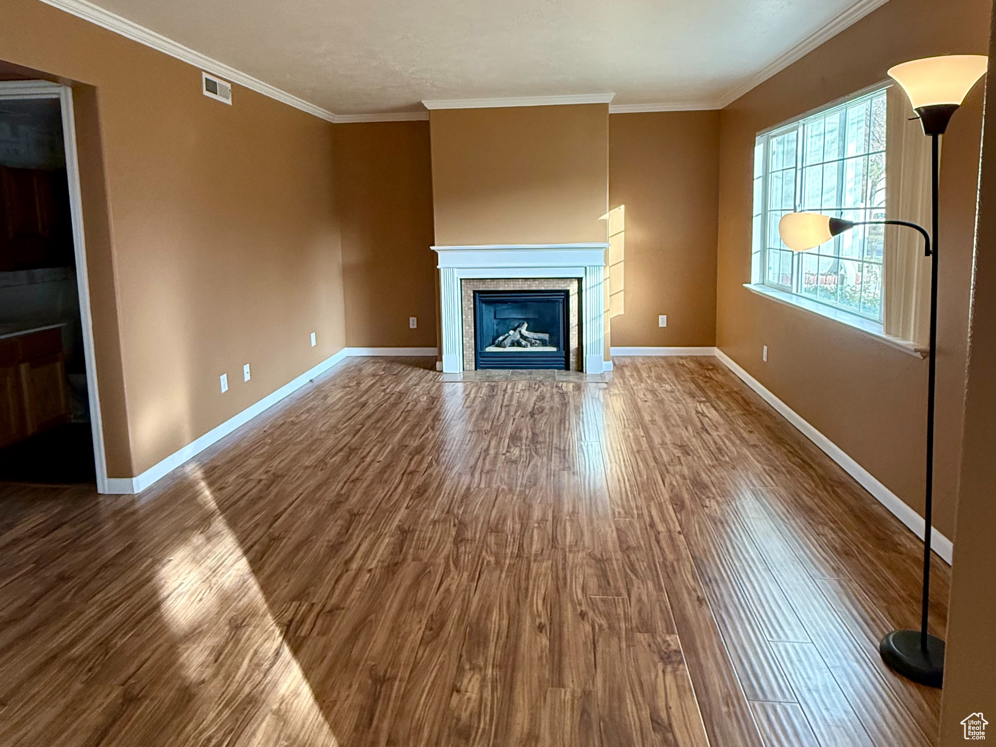 Unfurnished living room with hardwood / wood-style floors, crown molding, and a textured ceiling