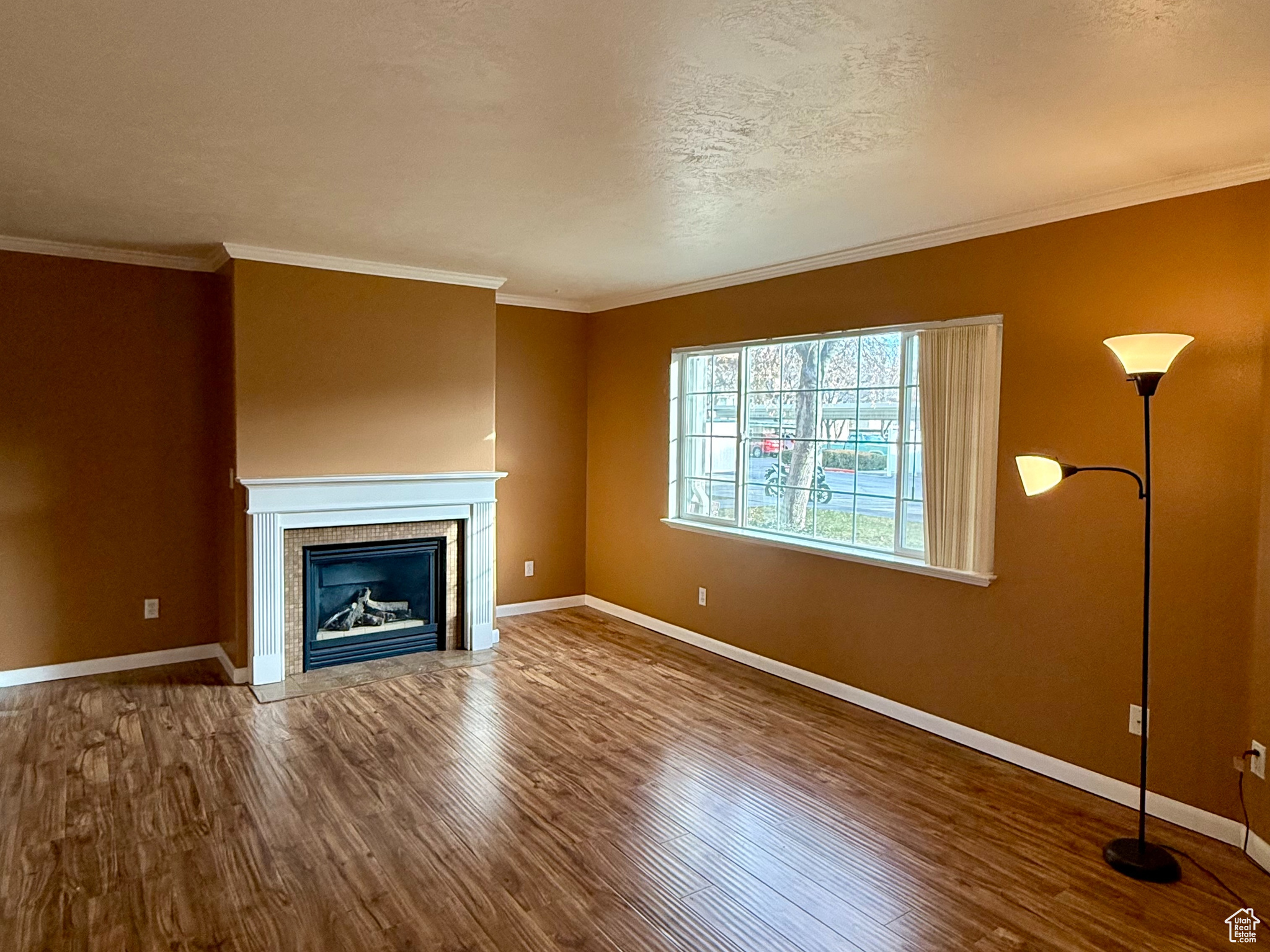 Unfurnished living room with hardwood / wood-style floors and crown molding