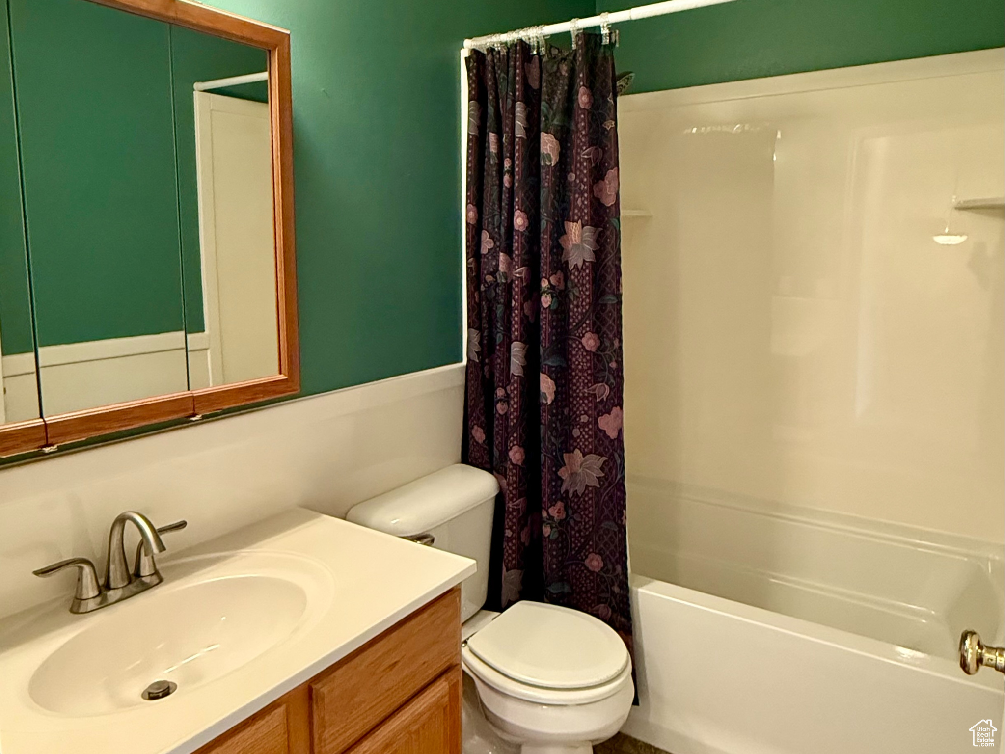 Full bathroom featuring vanity, toilet, and shower / bathtub combination with curtain