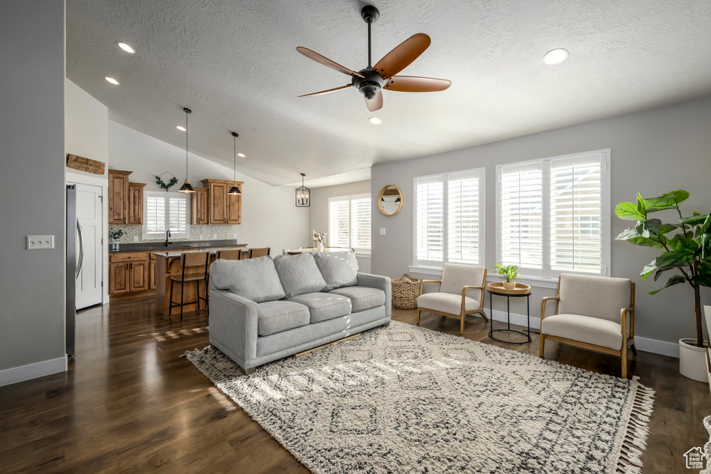 Living room with a wealth of natural light, ceiling fan, dark hardwood / wood-style flooring, and lofted ceiling