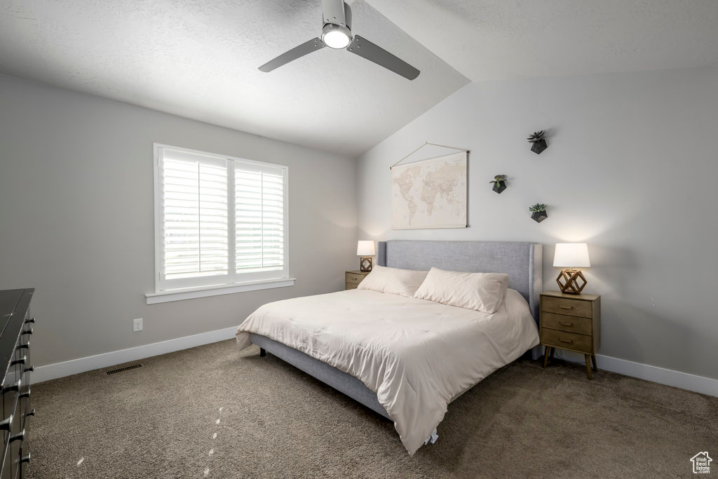 Bedroom featuring ceiling fan, lofted ceiling, and dark colored carpet