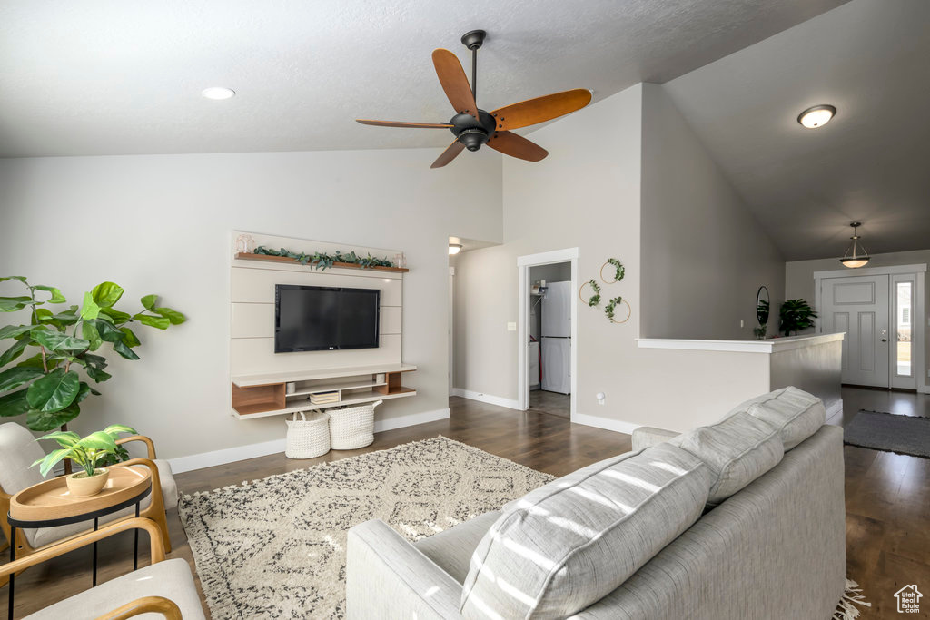 Living room with dark hardwood / wood-style flooring, vaulted ceiling, and ceiling fan