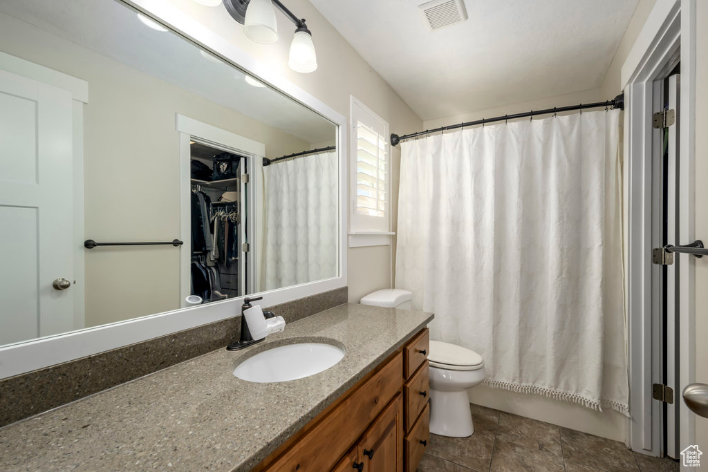 Bathroom featuring curtained shower, vanity, and toilet