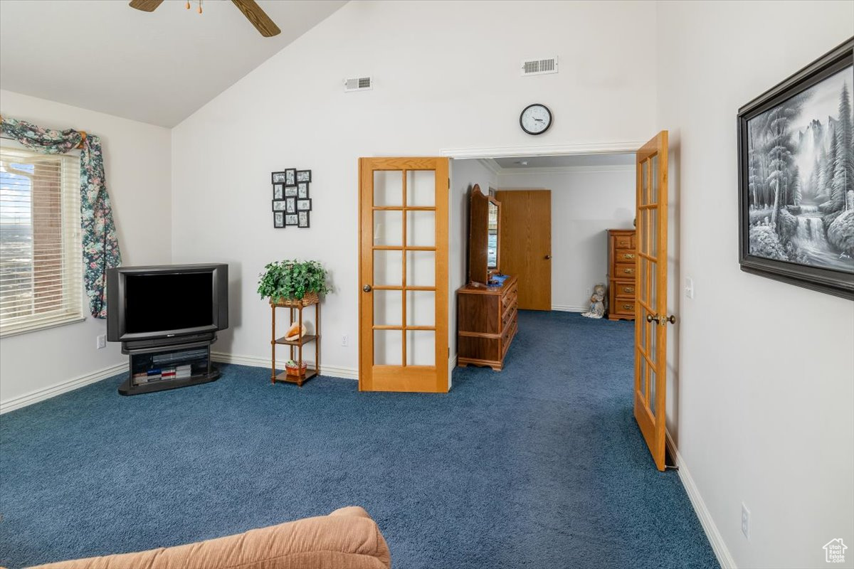 Living area featuring dark colored carpet, french doors, ceiling fan, and lofted ceiling