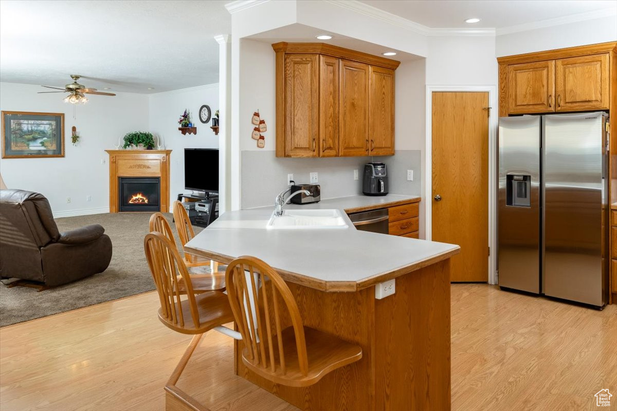 Kitchen featuring sink, ceiling fan, light wood-type flooring, kitchen peninsula, and stainless steel appliances