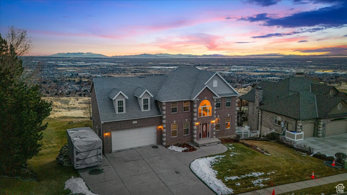 View of front of home with a mountain view, a garage, and a lawn