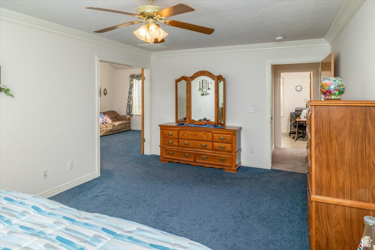 Carpeted Master Bedroom suite featuring ceiling fan, crown molding, and double doors to sitting room