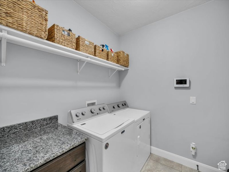 Washroom featuring washing machine and dryer and light tile patterned floors