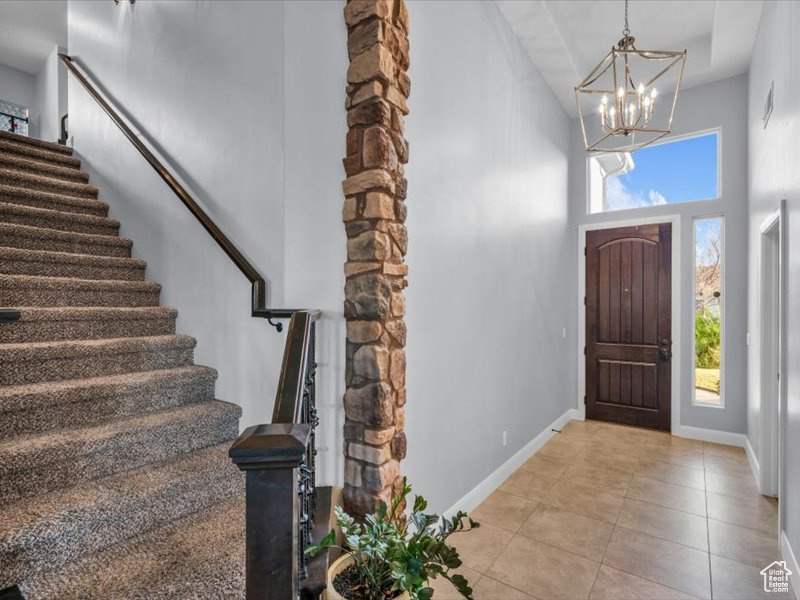 Tiled foyer with a towering ceiling and a chandelier