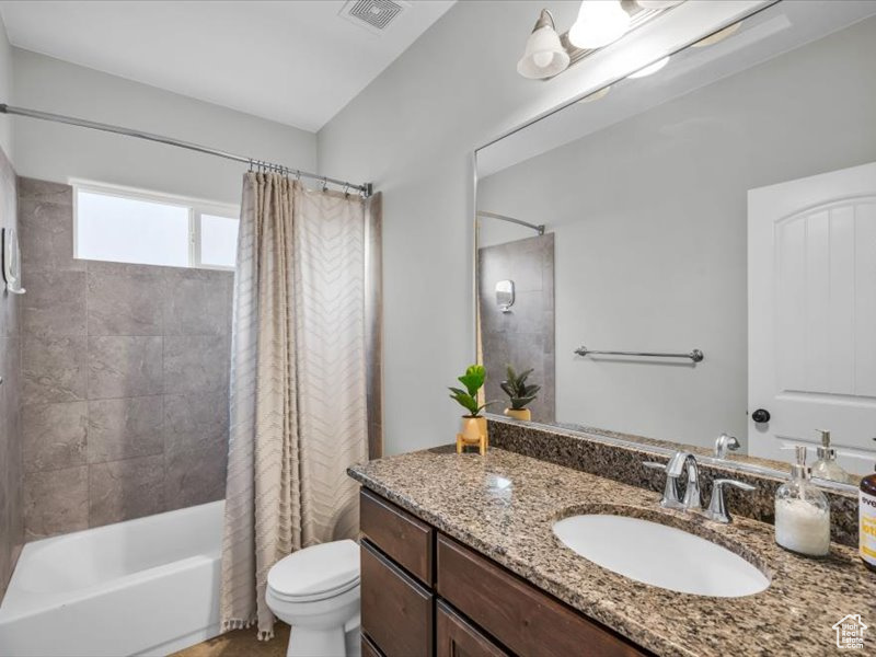 Full bathroom with shower / tub combo with curtain, vanity, and toilet