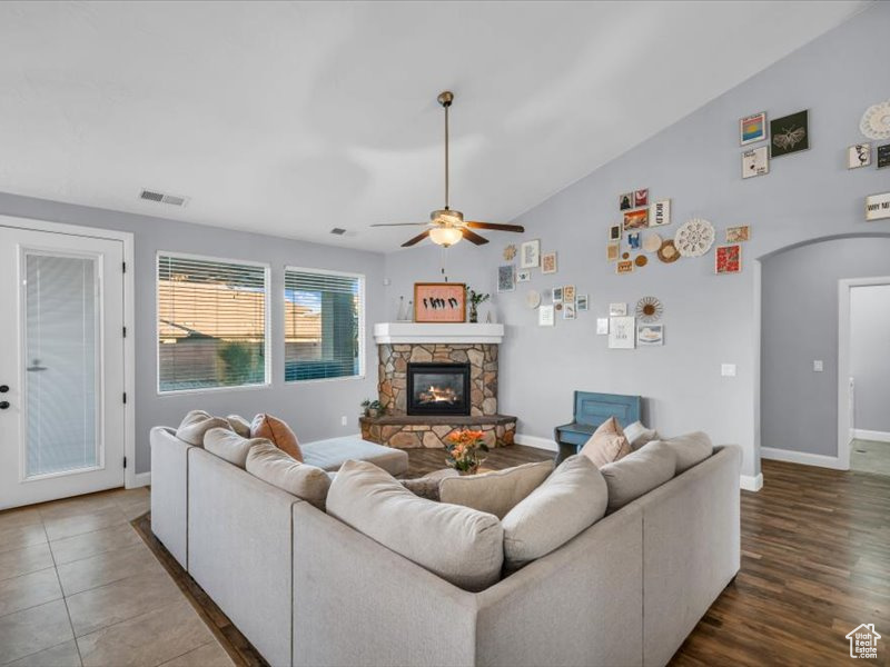 Living room featuring a fireplace, dark hardwood / wood-style floors, vaulted ceiling, and ceiling fan