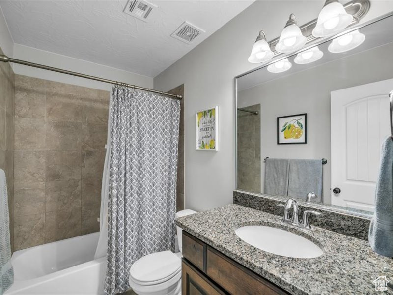 Full bathroom featuring vanity, toilet, and shower / bath combo with shower curtain