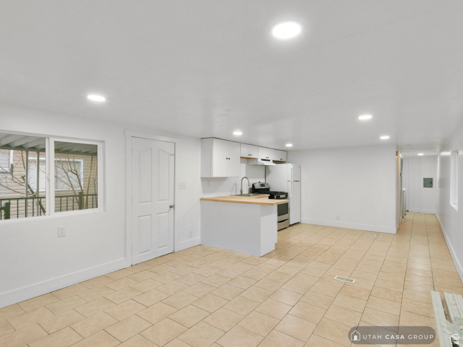 Kitchen featuring kitchen peninsula, gas stove, sink, white cabinets, and butcher block countertops