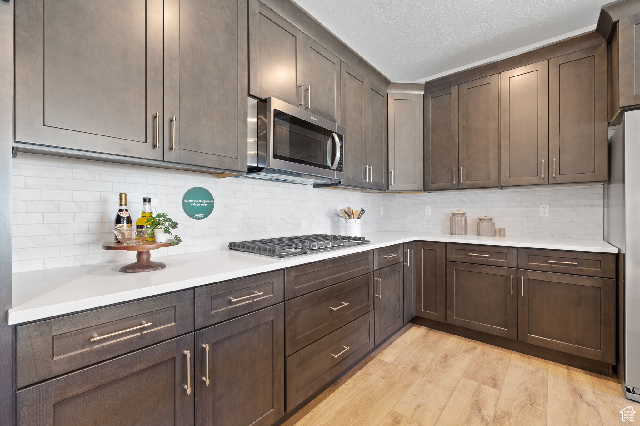 Kitchen featuring decorative backsplash, dark brown cabinets, and appliances with stainless steel finishes