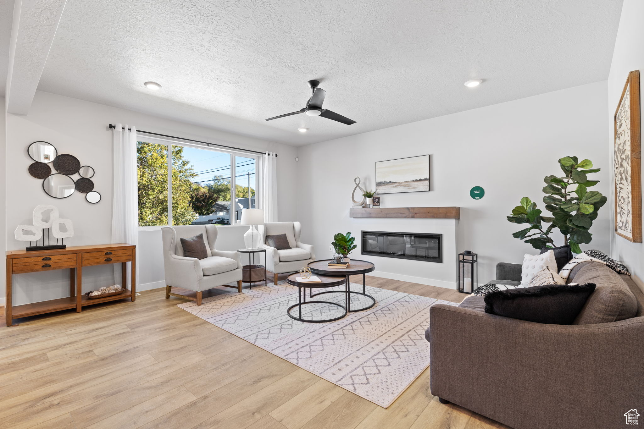 Living room featuring ceiling fan, a textured ceiling, and light hardwood / wood-style flooring