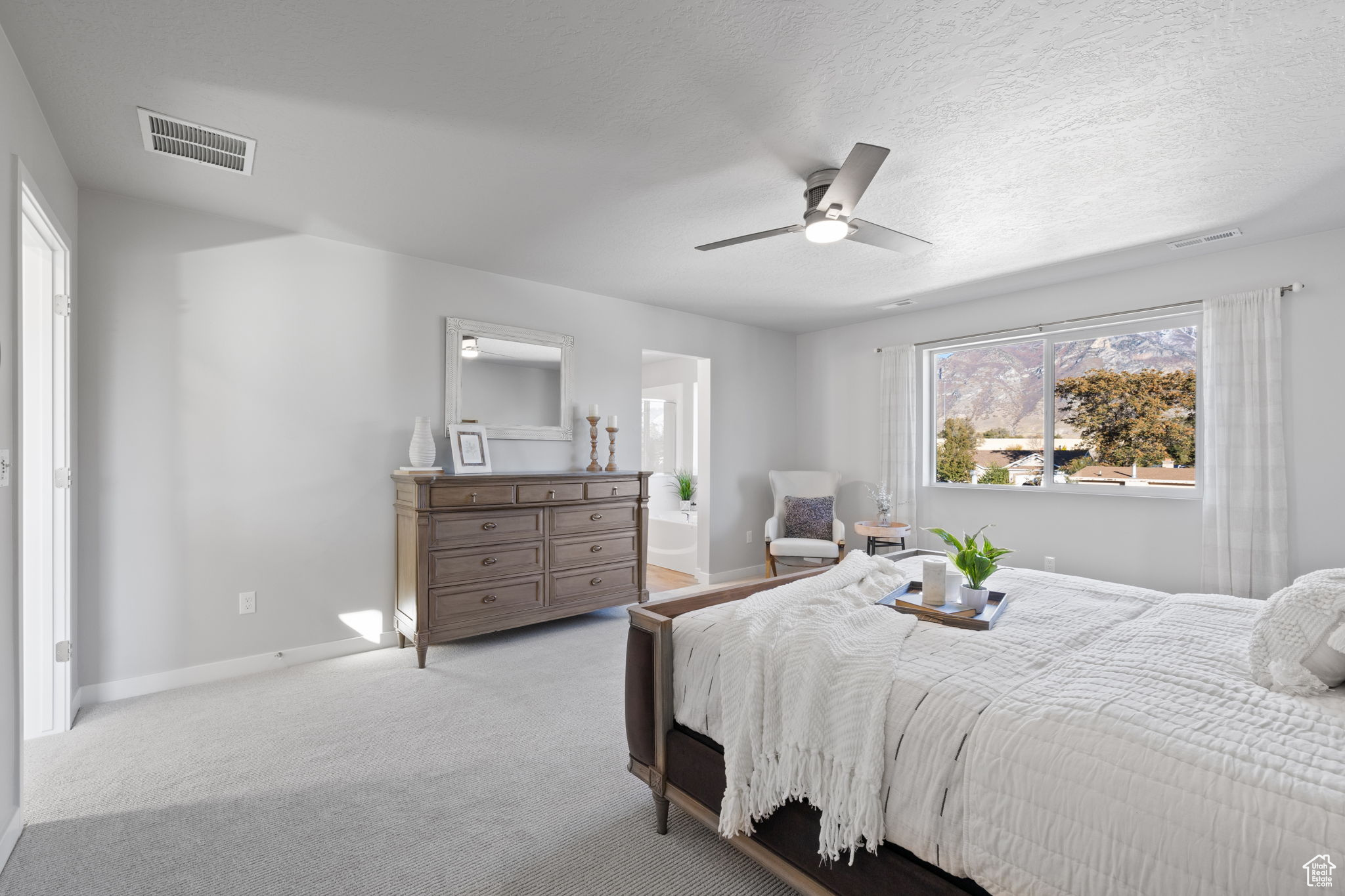 Bedroom featuring ceiling fan, light colored carpet, and a textured ceiling