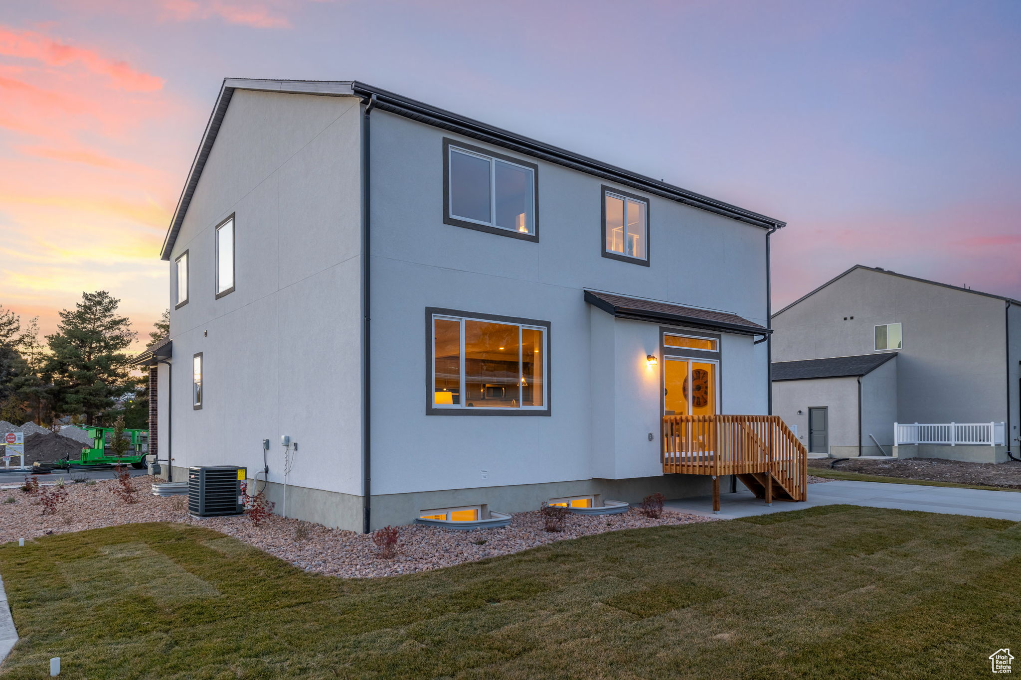 Back house at dusk featuring a lawn and central air condition unit