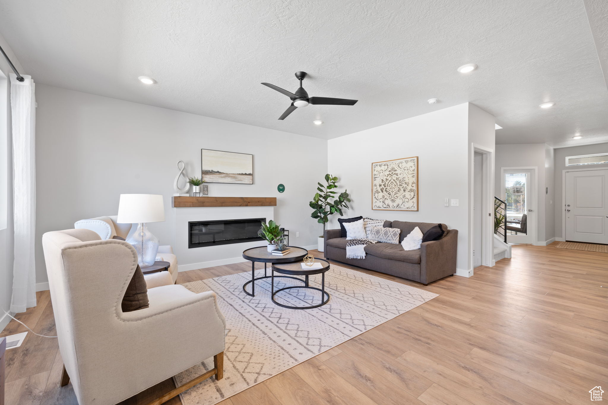 Living room with ceiling fan, light hardwood / wood-style floors, and a textured ceiling