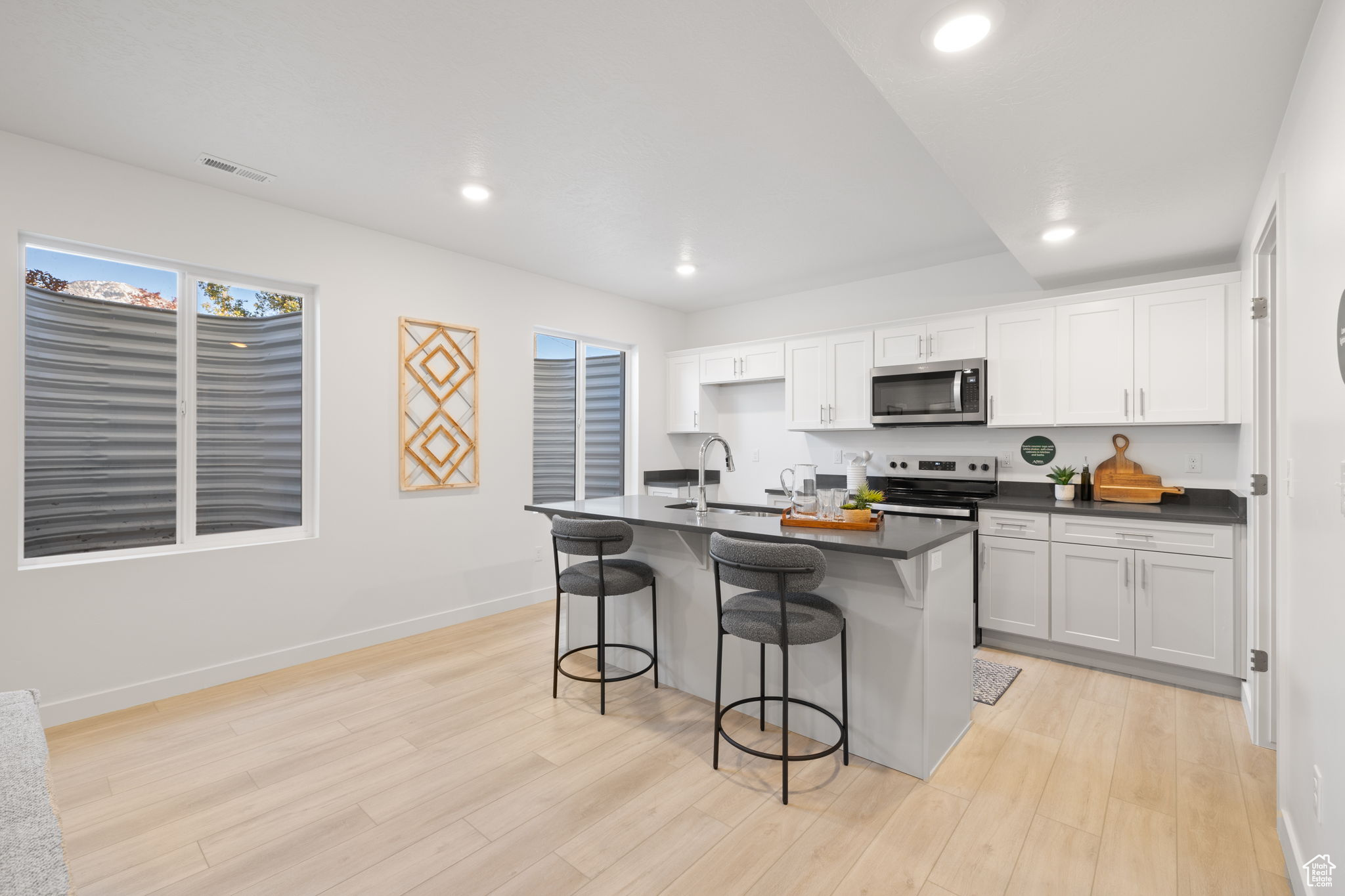 Kitchen featuring sink, stainless steel appliances, a kitchen breakfast bar, a kitchen island with sink, and white cabinets