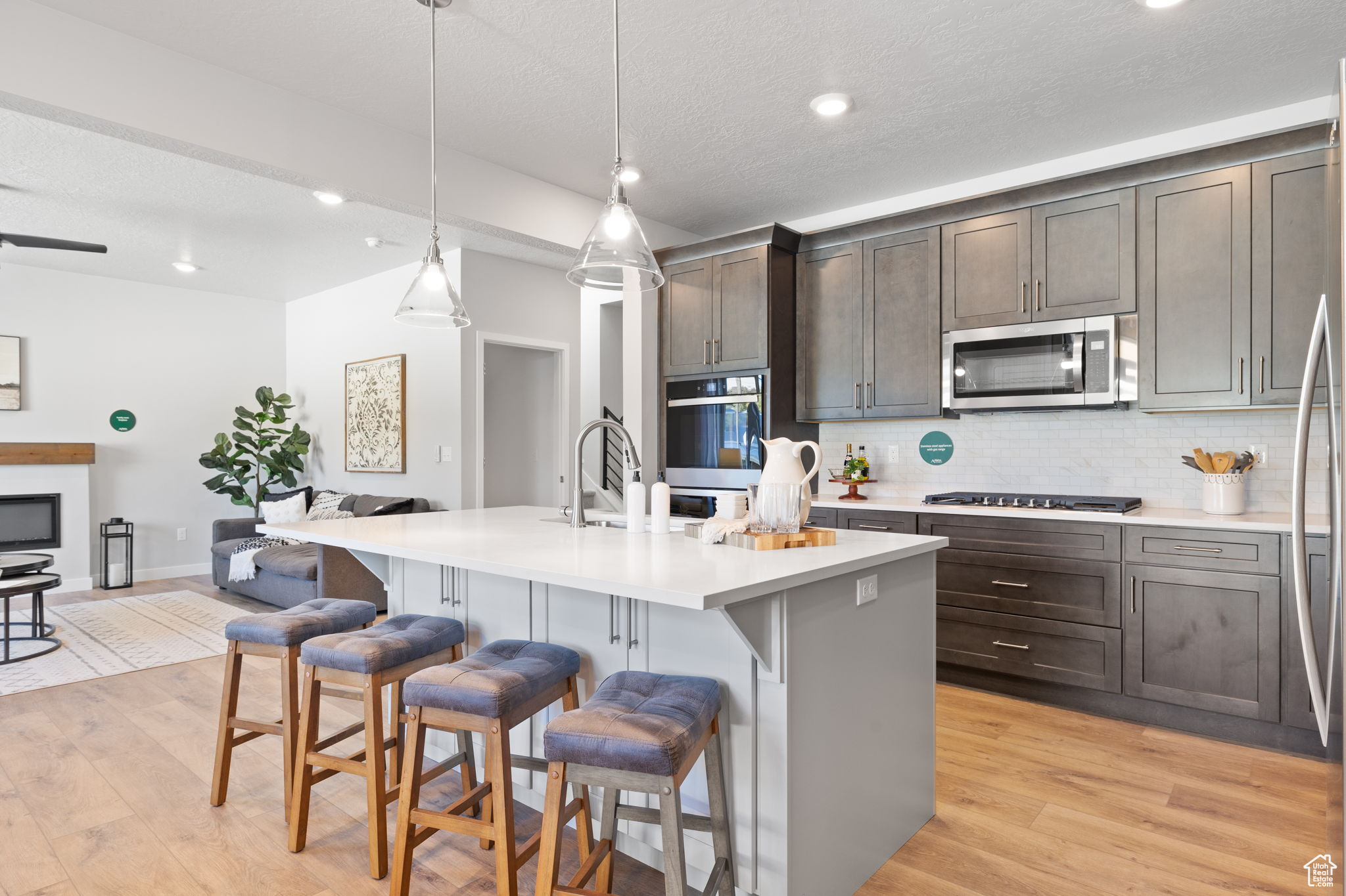 Kitchen with a center island with sink, a breakfast bar, pendant lighting, and appliances with stainless steel finishes