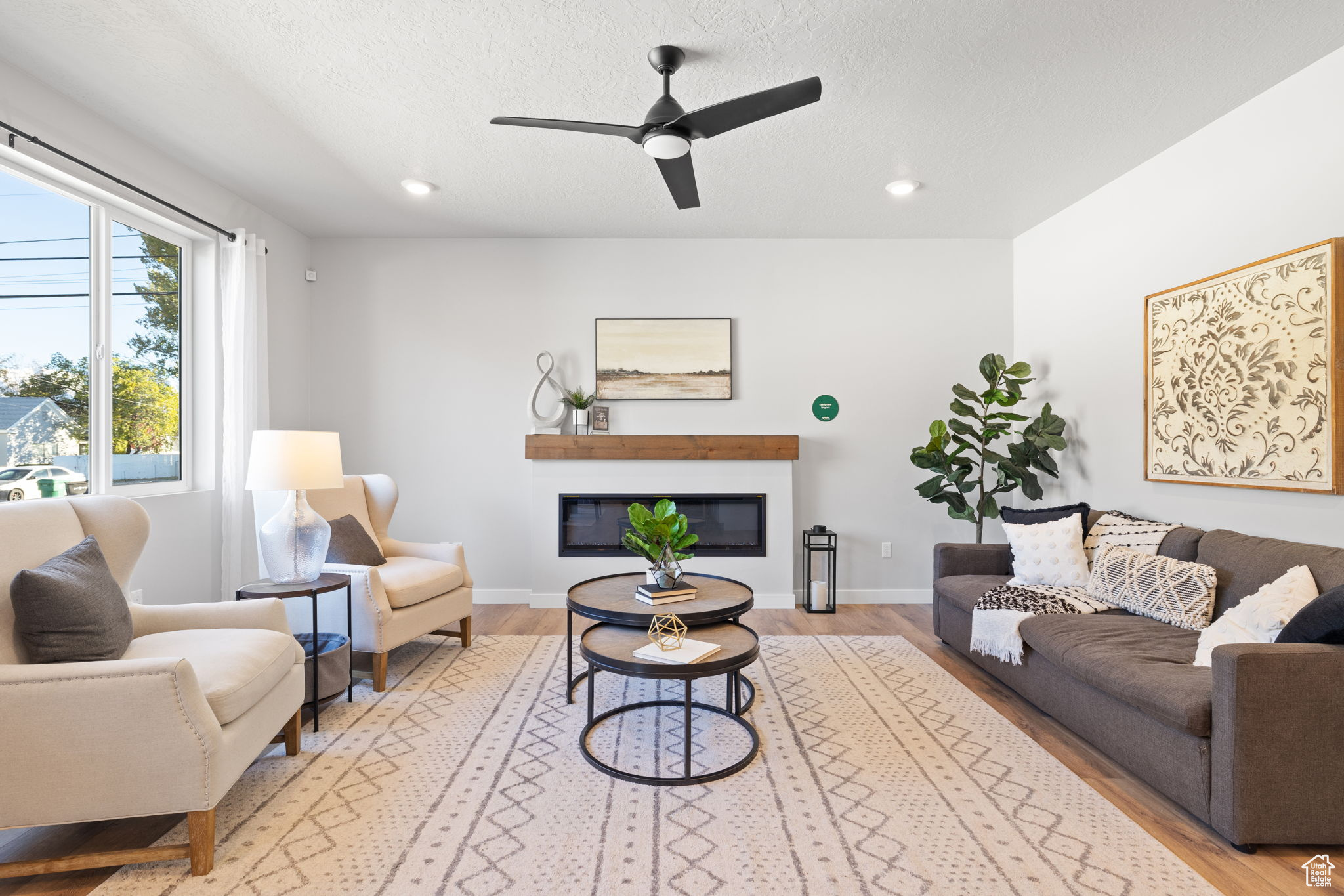 Living room featuring ceiling fan, light wood-type flooring, and a textured ceiling