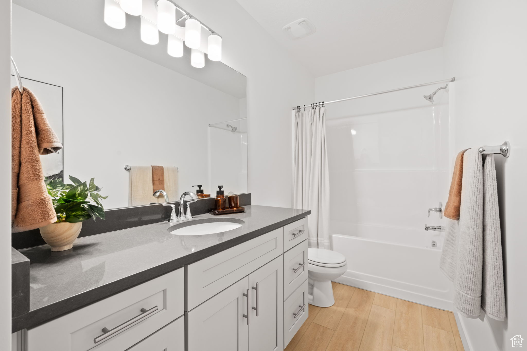 Full bathroom featuring hardwood / wood-style flooring, vanity, toilet, and shower / tub combo with curtain