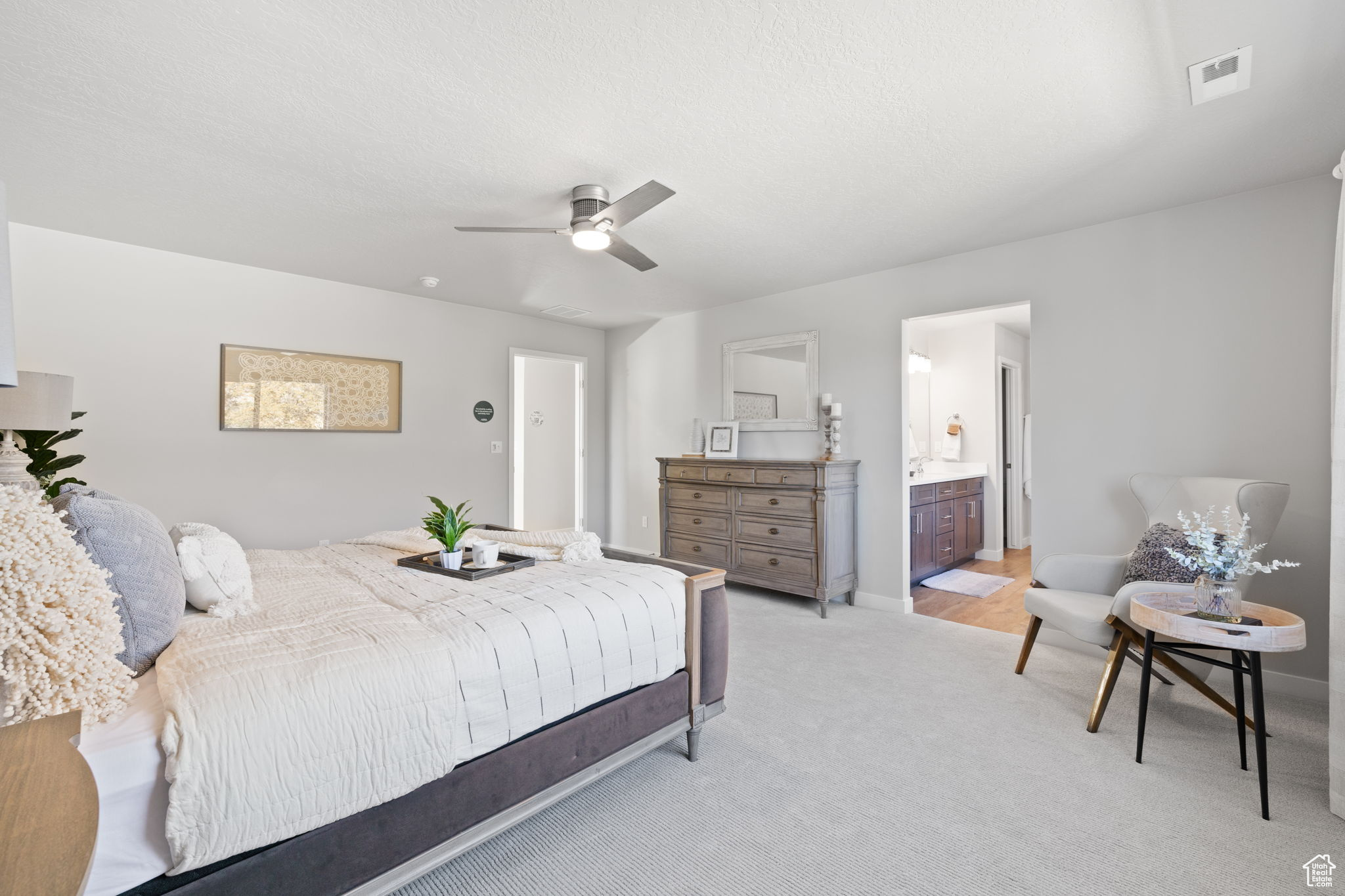 Carpeted bedroom with ensuite bathroom and ceiling fan