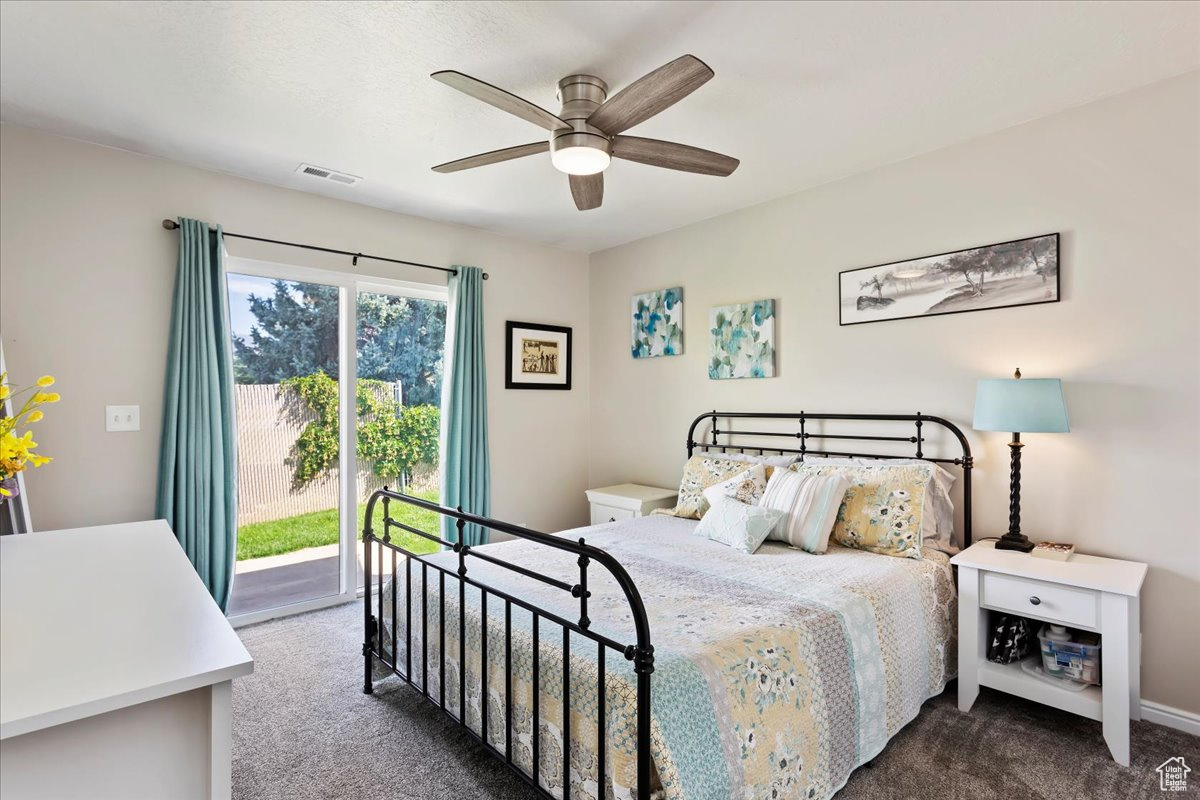 Bedroom featuring access to exterior, ceiling fan, and dark colored carpet