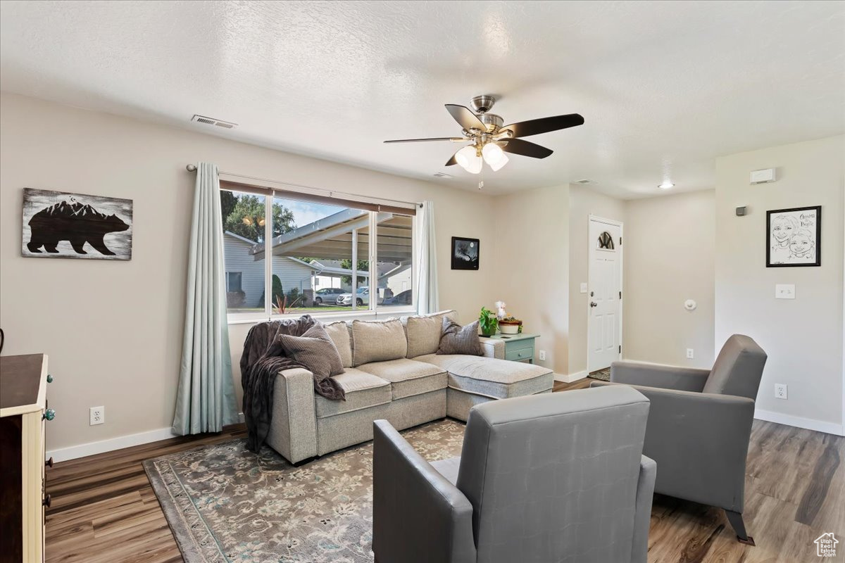 Living room with hardwood / wood-style flooring, ceiling fan, and a textured ceiling