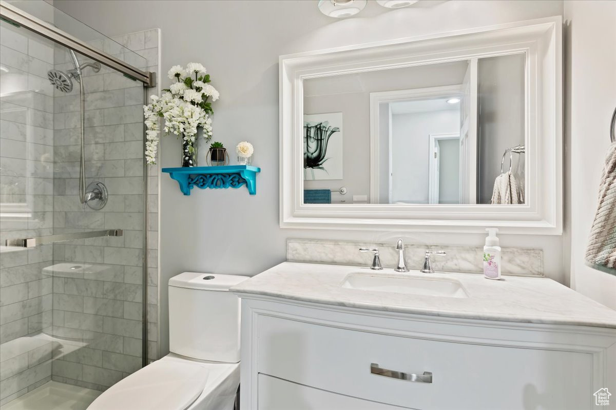 Bathroom with vanity, a shower with shower door, and toilet