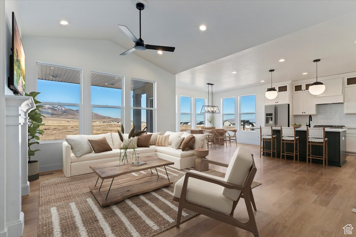 Living room featuring light wood-type flooring, vaulted ceiling, plenty of natural light, and ceiling fan