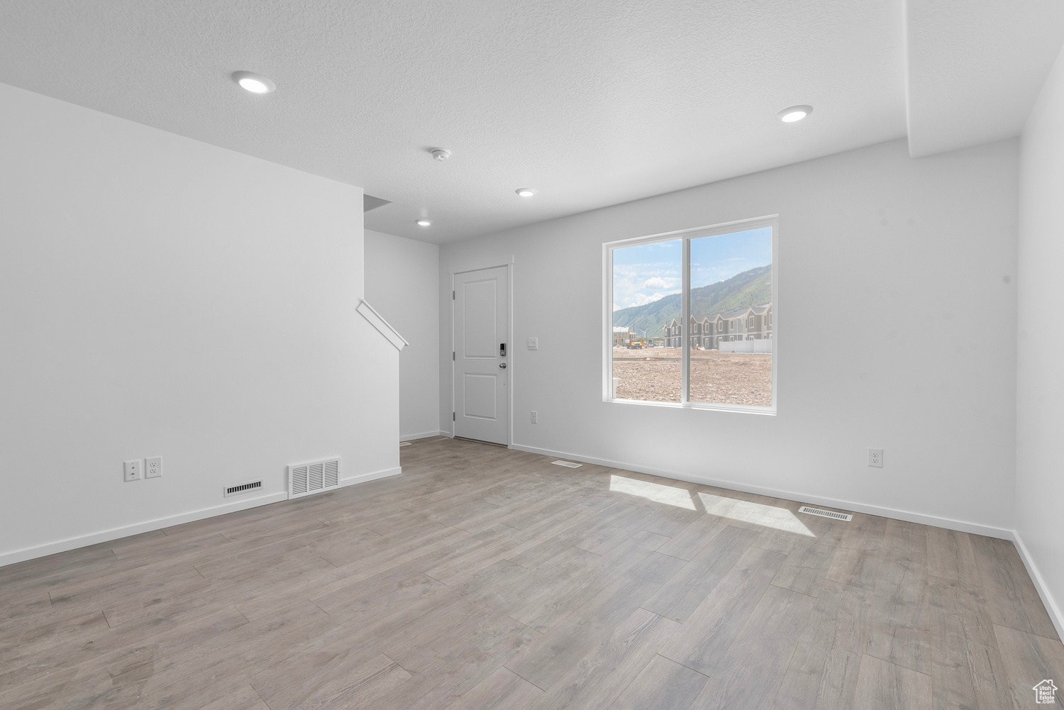 Unfurnished room with a mountain view, a textured ceiling, and laminate flooring